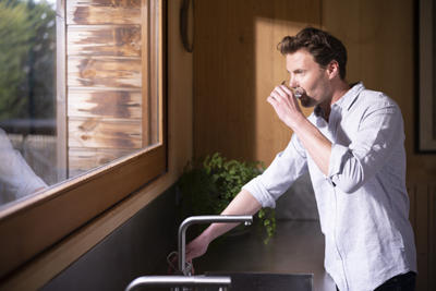 Man drinking a glass of water from the tap - municipal drinking water treatment.